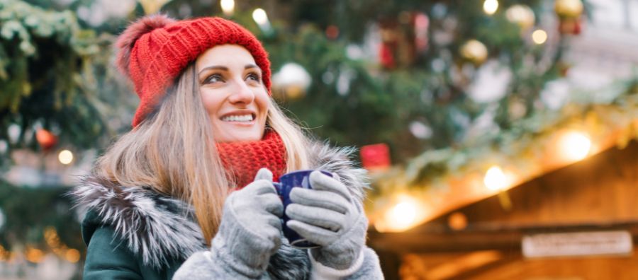 Single Frau trinkt auf dem Weihnachtsmarkt einen Glühwein - bei einem Date
